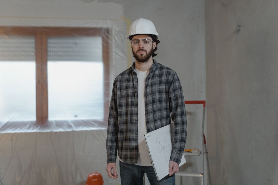 A contractor holding building plans in a room under renovation