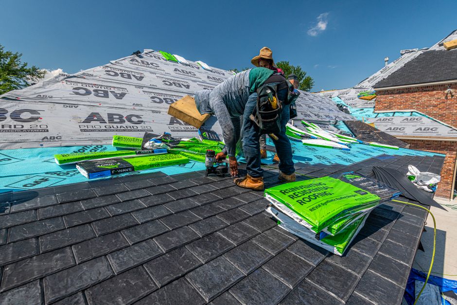 Roofers installing shingles on a house